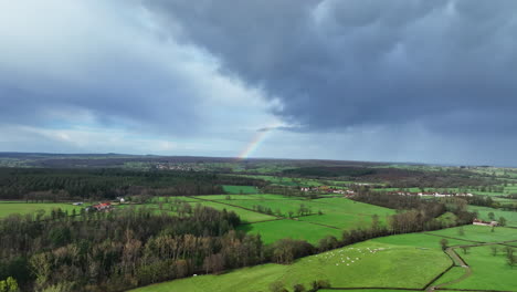 Beautiful-rainbow-over-fields-France-countryside-aerial-shot-cloudy-day
