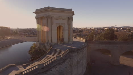 Beautiful-sunlight-flare-flying-over-water-tower-in-Montpellier-Peyrou-parc