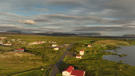 Myvatn-lake-in-Iceland-with-red-roofs-farmer-houses-empty-road-and-volcanic-hill