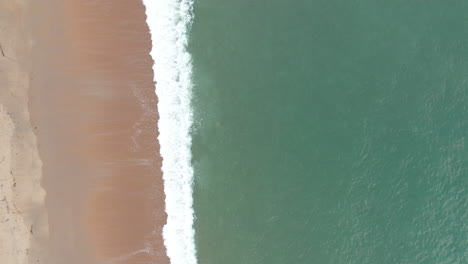 drone-shot-over-waves-crashing-on-a-sandy-beach-coast-Basque-province-of-Labourd