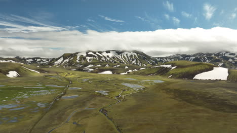Wet-highlands-in-Iceland-snowy-mountains-and-valley-landscape-aerial-shot-sunny