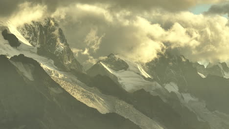 Wolken-über-Schneebedeckten-Bergen,-Französische-Alpen,-Stimmungsvolles-Licht,-Sonnenaufgang,-Goldene-Stunde,-Gelb