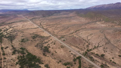 Endless-long-road-crossing-arid-environment-in-South-Africa-countryside-aerial-s
