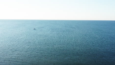 Blauer-Himmel-Und-Meer-Mit-Einem-Winzigen-Boot-In-Der-Sonne,-Luftaufnahme-Der-Mittelmeerküste