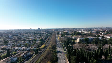 Long-straight-road-along-train-track-with-Montpellier-urban-city-backdrop