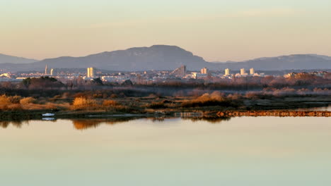 Montpellier-cityscape-with-mirrored-water-reflection,-framed-by-distant-peaks.