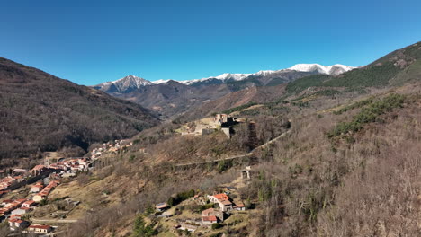 Panoramic-aerial-of-a-quaint-village-among-forested-hills.
