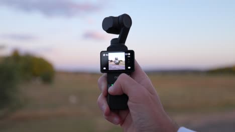 DJI-Osmo-Pocket-3-Wird-In-Der-Hand-Gehalten-Und-Der-Gimbal-Kopf-Wird-Durch-Drücken-Der-Taste-Mit-Dem-Finger-Bewegt