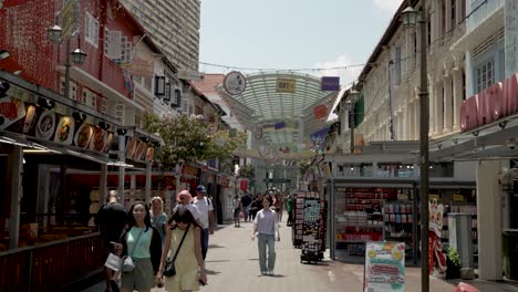 Tourists-Walking-Along-Pagoda-Street-On-Sunny-Afternoon-With-Chinatown-MRT-Station-Entrance-In-Background-In-Singapore