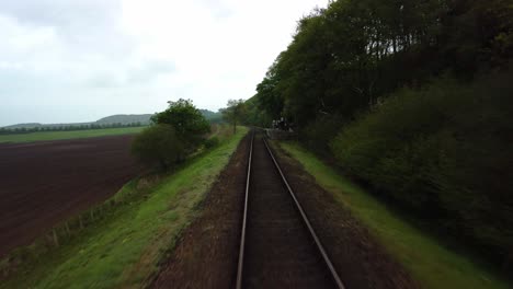 Aerial-Drone-4K-footage-racing-low-along-the-railway-of-the-Poppy-Line-track-between-Holt-and-Cromer,-North-Norfolk