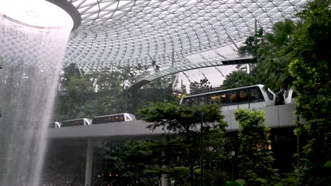 Der-Regenwirbel-Indoor-Wasserfall-Am-Jewel-Changi-Airport-Singapur-Mit-Vorbeifahrendem-Skytrain