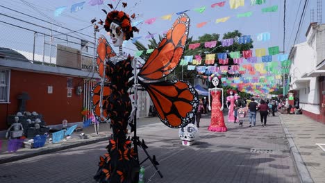 Day-of-the-Dead-statues-line-small-cobble-street-in-Mixquic,-Mexico