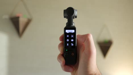Close-Up-View-Of-DJI-Osmo-Pocket-3-Held-In-Hand-And-Screen-Being-Flipped-From-Vertical-To-Landscape-Mode-And-Scrolling-Through-Screen-Icons-Indoors