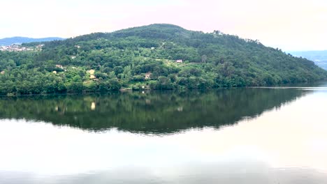 Ein-Majestätischer-Hügel-Mit-Viel-Grün,-Das-Sich-Im-Wasser-Des-Flusses-Douro-Spiegelt