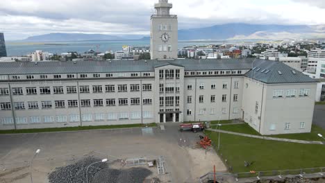 Eine-4K-Drohne-Gleitet-über-Das-Herz-Von-Reykjavik,-Während-Der-Große-Glockenturm-Als-Wache-Vor-Der-Ruhigen-Uferpromenade-Steht