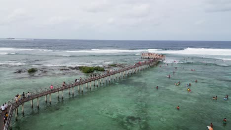 Drone-shot-of-people-walking-on-Siargao-Boardwalk-near-ocean,-Philippines