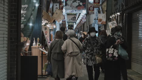 Local-Japanese-people-in-masks-strolling-and-shopping-in-the-indoor-Nishiki-Market-in-Kyoto,-Japan-during-the-pandemic