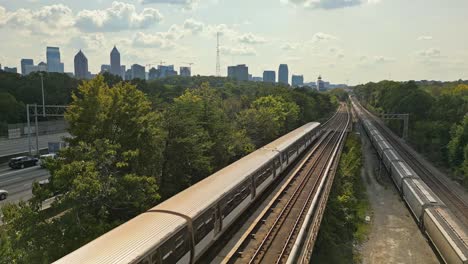 Luftaufnahme-Zeigt-Einen-Amerikanischen-Zug,-Der-An-Der-Eisenbahn-Vorbeifährt,-Mit-Der-Skyline-Von-Atlanta-Im-Hintergrund