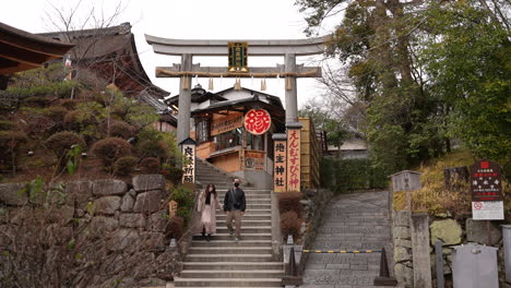 Young-Asian-couple-in-masks-walking-down-the-staircase-of-Jishu-jinja-Shrine-holding-hands-inside-Kiyomizudera-Temple-in-Kyoto