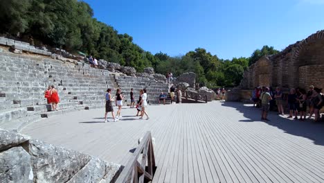 Reise-Durch-Die-Geschichte:-Touristen-Erkunden-Das-Antike-Amphitheater-Und-Die-Steinmauern-Von-Butrint,-Einer-Bezaubernden-Archäologischen-Stätte