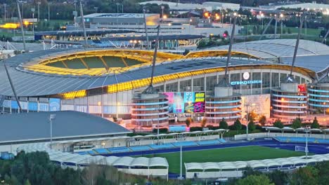 Weitwinkelaufnahme-Der-Drohne,-Die-Die-Beleuchtung-Des-Etihad-Stadions-Von-Manchester-City-Am-Abend-Zeigt