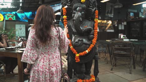 Una-Mujer-India-Que-Abraza-Plenamente-La-Cultura-Local-Mientras-Está-Sentada-En-Un-Bar-Tradicional-Local,-Acariciando-Suavemente-Una-Escultura-De-Ganesha-En-Panaji,-Goa,-India-El-31-08-2023