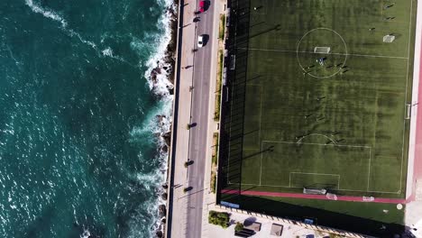 Wunderschönes-Blaues-Meer-Und-Grünes-Fußballfeld,-Luftaufnahme-Von-Oben-Nach-Unten