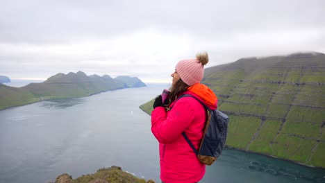 Woman-on-Klakkur-Mountain-top-enjoying-Faroese-landscape-view-holding-flask