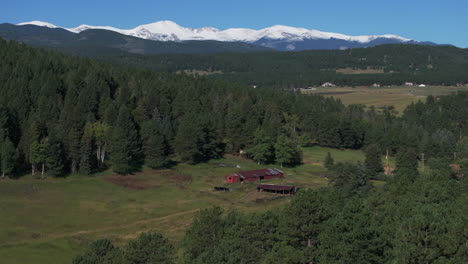 Cinematic-aerial-drone-red-barn-first-snow-on-Denver-Mount-Blue-Sky-Evans-14er-peak-early-autumn-fall-beautiful-blue-bird-clear-morning-sunrise-day-Colorado-Rocky-Mountains-forward-reveal-motion