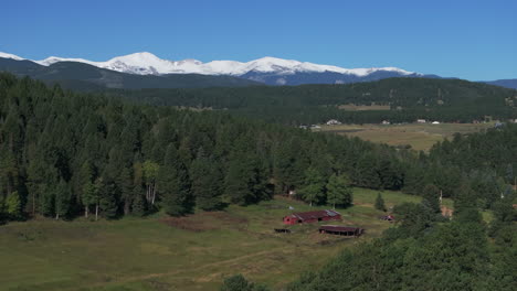 Cinematic-aerial-drone-red-barn-first-snow-on-Denver-Mount-Blue-Sky-Evans-14er-peak-early-autumn-fall-beautiful-blue-bird-clear-morning-sunrise-day-Colorado-Rocky-Mountains-circle-slowly-right-motion