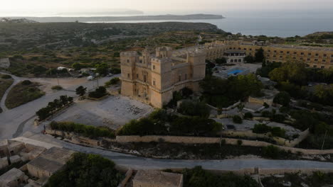 Aerial-view-tilting-toward-the-Selmun-Palace,-golden-hour-on-the-Malta-island