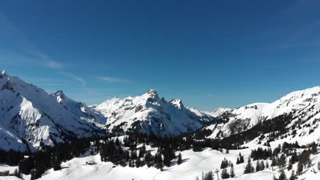 Vista-Por-Drones-De-Cadenas-Montañosas-Cubiertas-De-Nieve-En-Warth,-Un-Pequeño-Municipio-En-Vorarlberg,-Austria,-En-Un-Día-Maravillosamente-Claro-Y-Soleado-En-4k