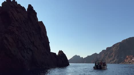 Tour-boat-at-Scandola-peninsula-nature-reserve-in-summer-season,-Corsica-island-in-France