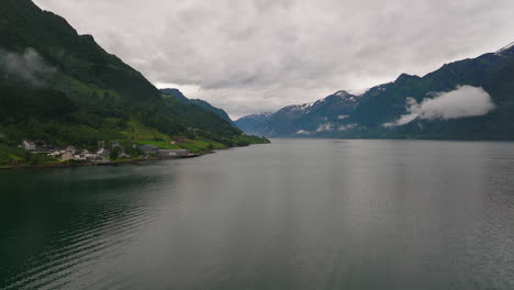 Nordic-fjord-in-beautiful-aerial-scene-as-drone-follow-scenic-coastline-with-mountain-backdrop