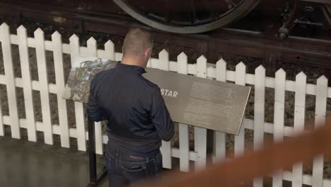 static-shot-of-a-tourist-reading-a-sign-at-The-National-Railway-Museum-In-York