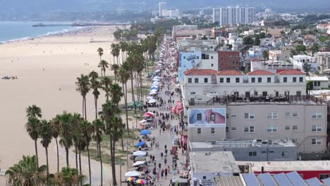 Overlooking-the-famous-Venice-Beach-Boardwalk,-crowded-with-people,-aerial-static-view