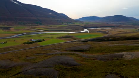 Aerial-revealing-shot-of-a-river-running-through-a-mountain-valley-in-Iceland