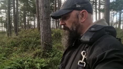 Hombre-Barbudo-Con-Gorra-De-Béisbol-Caminando-Pacíficamente-En-El-Bosque-Salvaje,-Anglesey,-Reino-Unido