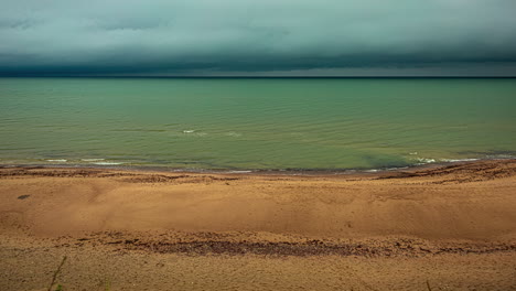 Timelapse-shot-of-dark-cloud-moving-over-sea-shore-with-waves-crashing-on-a-rainy-day