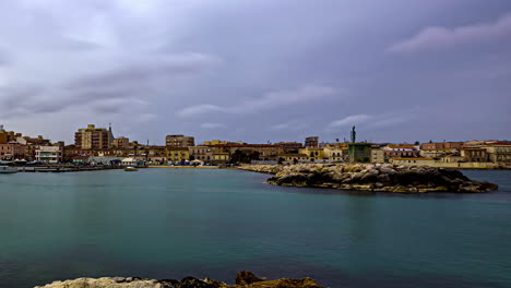 A-Time-Lapse-Shot-Of-A-Rocky-Coast-With-A-Chain-Of-Buildings-At-The-Shore-In-Italy