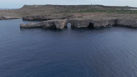 Aerial-over-calm-blue-waters-and-rock-formations-at-Pont-den-Gil