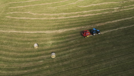 Stunning-cinematic-shot-of-fall-farmlands-tended-by-a-tractor-and-straw-press