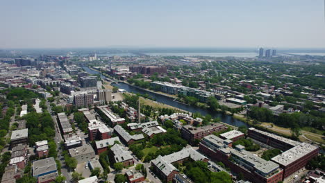 Aerial-tracking-shot-of-the-Lachine-Canal-and-Pointe-Saint-Charles,-in-sunny-Montreal