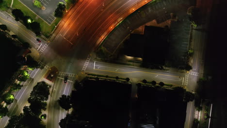 Top-down-view-of-low-traffic-on-road-and-empty-car-park-in-shopping-park-at-night