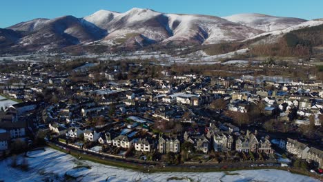Cinematic-aerial-4K-drone-video-of-Keswick-Town-in-winter,-with-Skiddaw-coated-in-snow-in-the-background