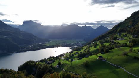 Sideways-aerial-pan-over-majestic-alpine-valley,-mirror-like-lake-below