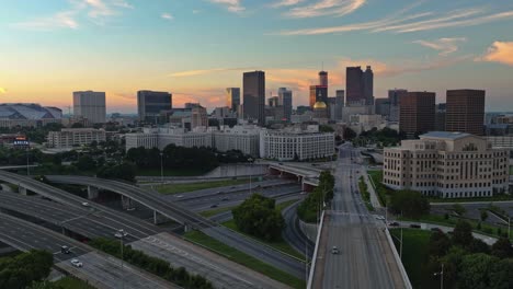 Hyperlapse-drone-shot-of-high-frequented-highway-and-lighting-Modern-Skyline-of-Atlanta-City-in-background-during-golden-Sunset---Panning-drone-shot