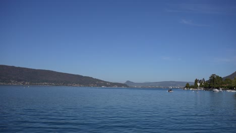 Lake-Annecy-in-the-French-Alps-with-boat-parked-right,-Wide-stable-shot