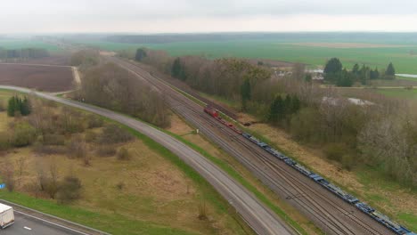 Highway-road-and-cargo-train-bellow,-aerial-view