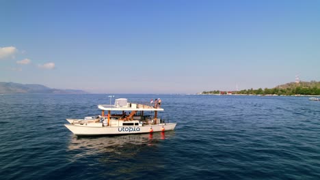 Travel-Couple-Sailing-on-Catamaran-Ship-Around-the-Gili-Islands-in-Lombok-Indonesia---Aerial-reveal-from-close-up-to-wide-angle